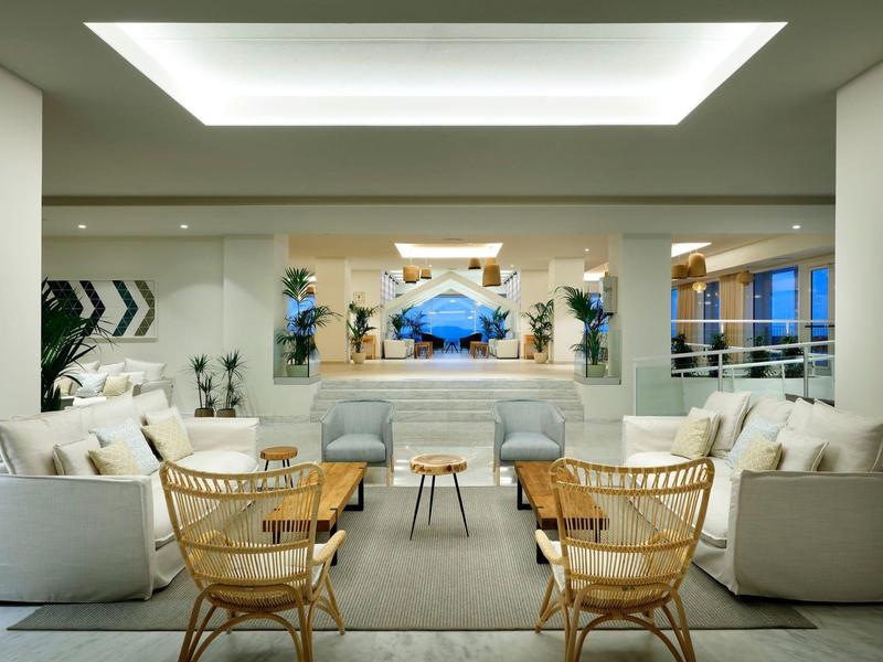 Elegancki salon z wiklinowymi fotelami i kremowymi sofami, nowoczesny wystrój, naturalne światło.