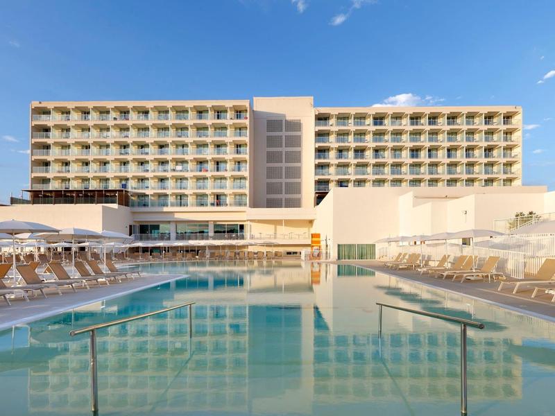 Nowoczesny hotel z zewnętrznym basenem i leżakami pod jasnym niebem.