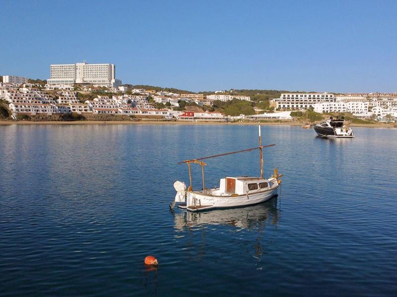 Łódź na spokojnej wodzie przy słonecznej wiosce nadmorskiej.