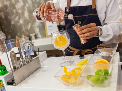 Barista prepara drink con ghiaccio e frutta al bancone.