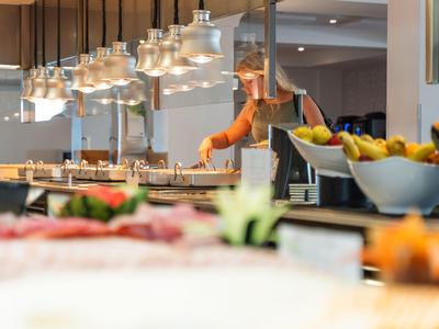 Cucina moderna dell'hotel con chef e lampade a sospensione eleganti sopra l'area di lavoro.