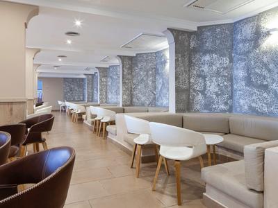 Area lounge dell'hotel arredata in modo moderno con sedie e tavoli confortevoli lungo una parete