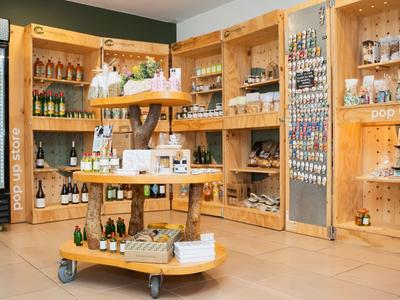 Negozio dell'hotel con scaffali in legno che mostrano bevande e souvenir, con un tavolo espositivo girevole.