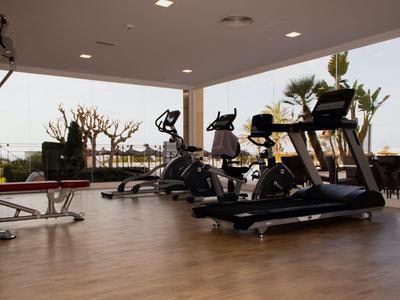 Palestra moderna con vista sulla terrazza esterna e piante, attrezzata con tapis roulant e altre macchine.