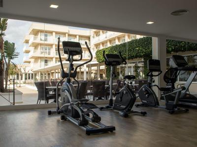 Palestra con attrezzature moderne e vista sulla terrazza dell'hotel.