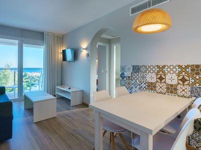 Stanza luminosa con zona pranzo e piastrelle colorate, vista su balcone e paesaggio esterno.