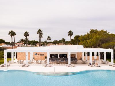 Bâtiment d'hôtel blanc moderne avec piscine et palmiers dans un cadre de vacances.