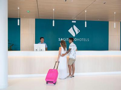 Deux femmes avec bagages se tiennent à la réception d'un hôtel moderne.