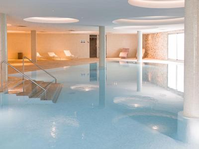Piscine intérieure moderne avec chaises longues et éclairage chaleureux dans un hôtel