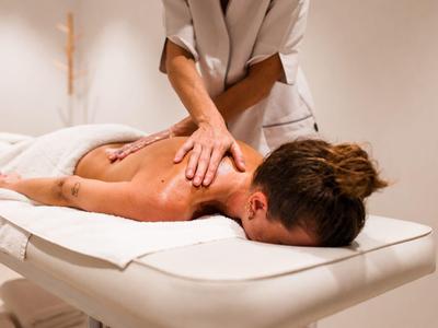 Personne reçoit un massage du dos dans un espace bien-être calme et lumineux.