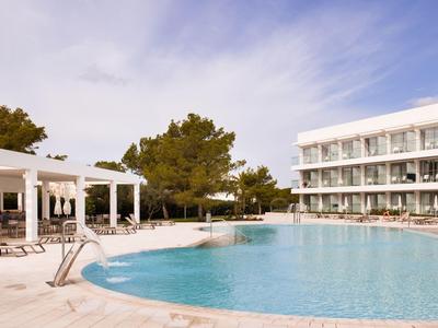 Piscine d'hôtel moderne avec chaises longues et espace couvert sous un ciel dégagé.