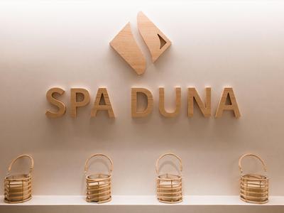 Intérieur d'un spa avec un logo en bois et quatre paniers décoratifs accrochés au mur.