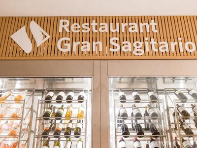 Casier à vin avec diverses bouteilles sous le panneau du restaurant Gran Sagitario.