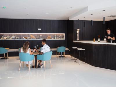 Café d'hôtel moderne avec des chaises bleues, murs noirs et clients à table.