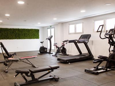 Salle de sport lumineuse avec équipements d’exercice et un mur végétal en arrière-plan.