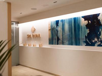 Entrée moderne d'hôtel ou spa avec une œuvre murale abstraite et un comptoir de réception blanc.