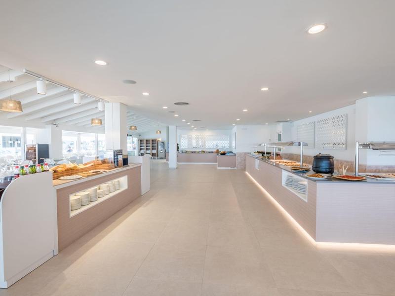 Área de buffet de hotel moderna y luminosa con varias estaciones de comida y diseño minimalista.