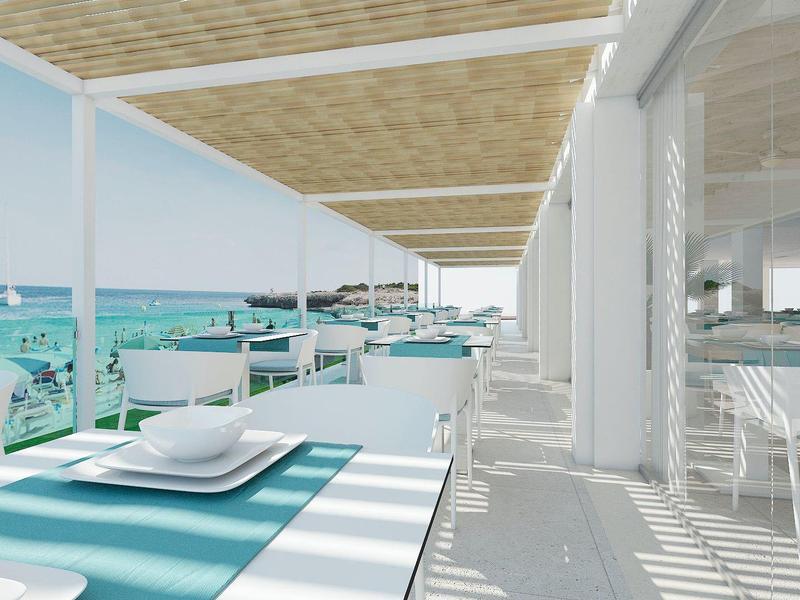 Bar de playa luminosa con mesas azul y blanco y vista al mar turquesa.