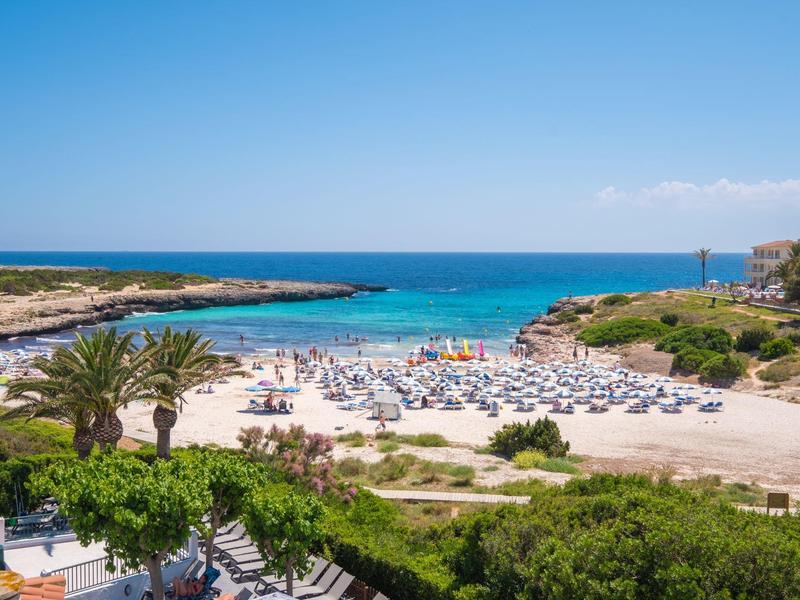 Playa con sombrillas junto al mar turquesa y cielo despejado en la costa.