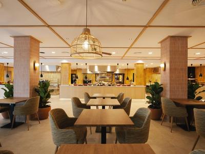 Espace lounge d'hôtel moderne et spacieux avec tables, chaises et éclairage chaleureux.