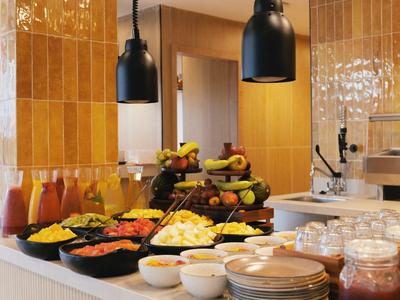 Buffet avec fruits frais, jus, céréales et bols dans un restaurant d'hôtel.