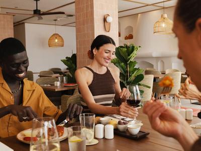 Trois personnes partagent un repas dans un restaurant moderne avec un éclairage chaleureux.