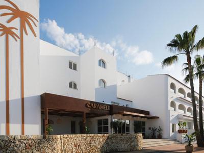 Bâtiment d'hôtel blanc moderne avec décoration de palmiers et ciel dégagé en arrière-plan.