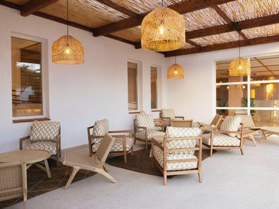 Terrasse couverte avec plafond en bois et sièges confortables pour les clients de l'hôtel.