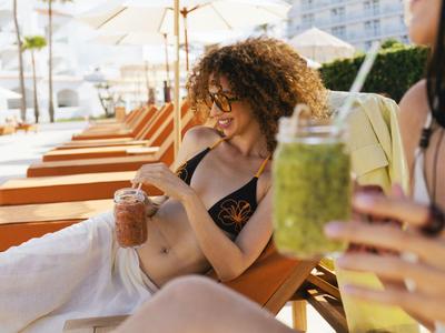 Deux femmes se détendent sur des chaises longues au bord de la piscine en dégustant des cocktails rafraîchissants.