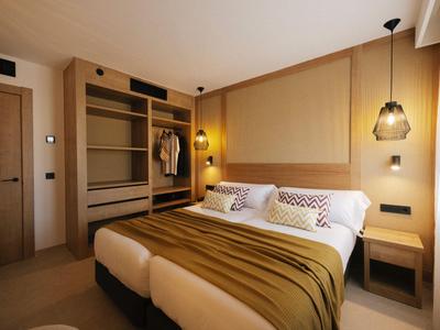 Chambre d'hôtel moderne avec deux lits simples, accents de bois chaleureux et éclairage cosy.