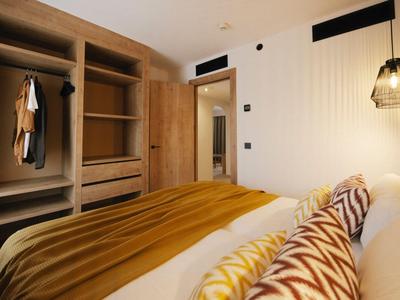 Chambre d'hôtel confortable avec garde-robe ouverte et tons chauds et terreux.