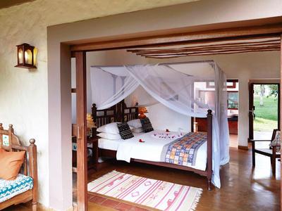 Gemütliches Schlafzimmer mit Himmelbett, Holzmöbeln und offenem Zugang zu einer Terrasse.