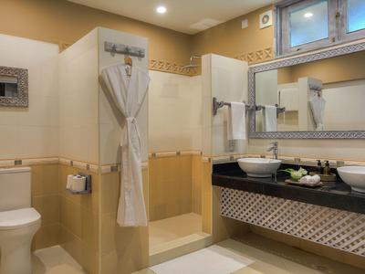 Helles Badezimmer mit Dusche, Toilette und Doppelwaschbecken mit großem Spiegel.