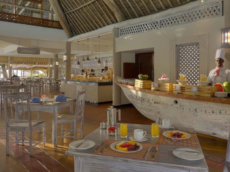 Helles Restaurant mit Holzboden, gedeckten Tischen und Buffet in Bootform an Wand mit großen Fenstern.