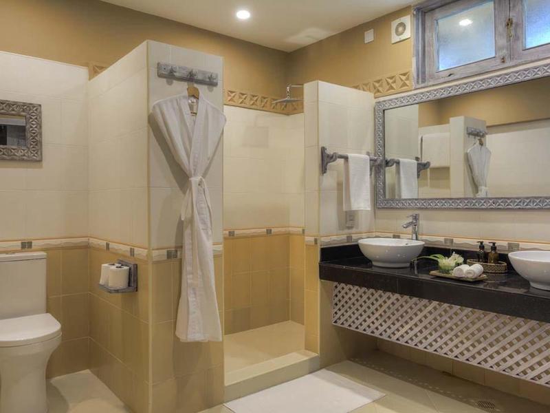 Moderne Badezimmer mit Duschkabine, zwei Waschbecken, WC und großen Spiegeln, beige Wandfliesen.