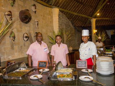 Tre membri dello staff in uniforme sono dietro un buffet in un ristorante rustico.