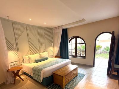 Camera d'hotel luminosa con letto matrimoniale, motivi murali moderni e finestre dal pavimento al soffitto.