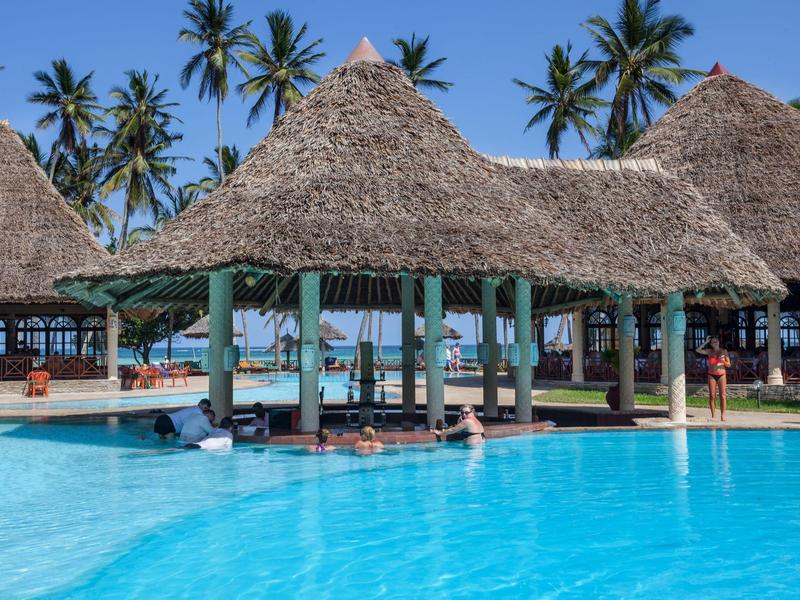 Bar piscina con tetto di paglia e acqua blu chiara, circondata da palme nel resort