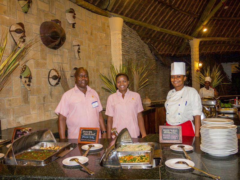 Tre membri dello staff in uniforme sono dietro un buffet in un ristorante rustico.
