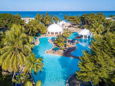 Velký bazén s palmami a bílými altány u moře