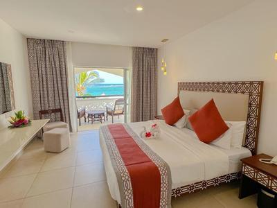 Moderní hotelový pokoj s manželskou postelí, balkonem a výhledem na moře, světlý interiér.