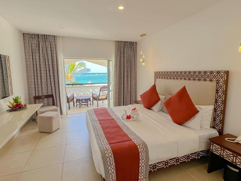 Moderní hotelový pokoj s manželskou postelí, balkonem a výhledem na moře, světlý interiér.