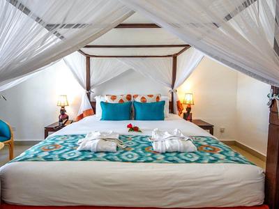 Schlafzimmer mit Himmelbett, türkisgemustertem Bettbezug und weißen Vorhängen, zwei Handtücher liegen.