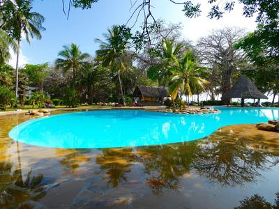 Rundes Schwimmbecken mit klarem, blauem Wasser, umgeben von Palmen und grüner Vegetation.