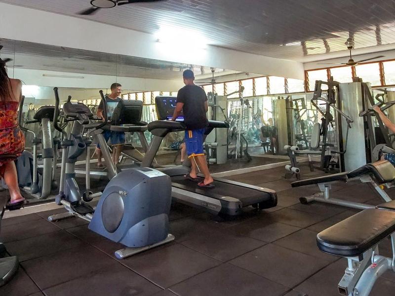 Innenraum eines Fitnessstudios mit Sportgeräten und mehreren Personen beim Training.