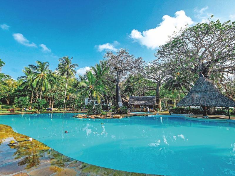 Großer Pool mit Palmen und Sonnenschirmen unter blauem Himmel in tropischem Resort