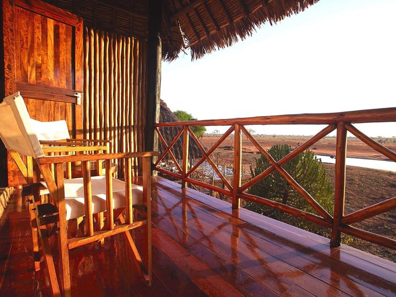 Balkon einer Lodge mit Holzstuhl und Blick auf die Küste bei Sonnenuntergang.