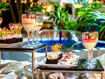 Elegante Dessertauswahl mit Schokolade, Creme und Früchten auf glänzenden Tabletts neben Pool.
