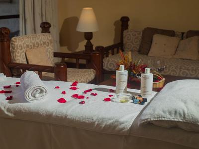 Ein Massagetisch mit weißen Handtüchern, Rosenblättern und Lotionflaschen in einem gemütlichen Raum.