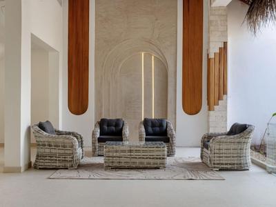 Eleganter Sitzbereich mit Rattanstühlen und einem Couchtisch vor einer architektonischen Wand.